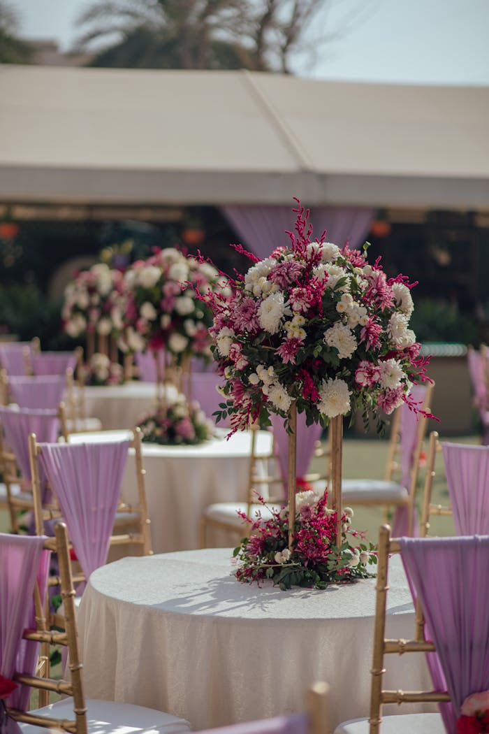 services-bg Chic wedding setup with floral centerpiece and lavender chairs outdoors.