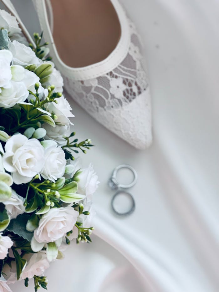 embark Elegant wedding setup featuring a white bouquet, lace shoe, and rings.